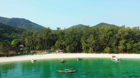 在平静美丽的海湾上停泊的渔船和旅游船，绿色的水冲刷着tro的白沙