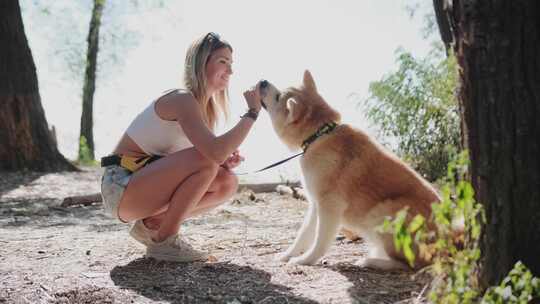 快乐的年轻女子在公园户外训练她的狗Aki