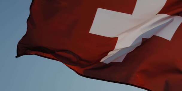 阳光明媚的一天，瑞士国旗在户外旗杆上挥舞