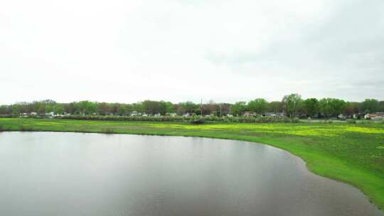 空中无人机拍摄的湖泊飞向高速公路和居民区，中间有一片草地