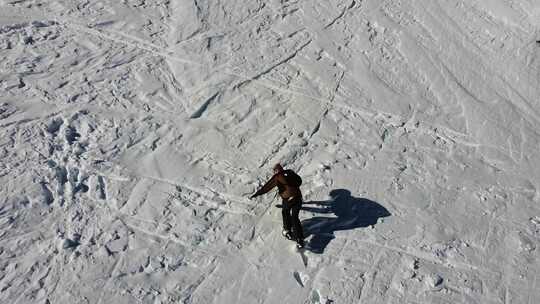 一个男人爬白雪覆盖的山的无人机视图