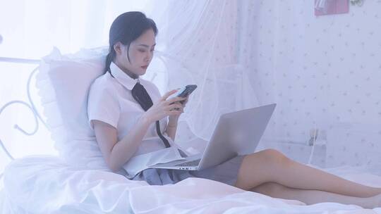 一名东方女性在卧室床上坐着玩手机视频素材模板下载
