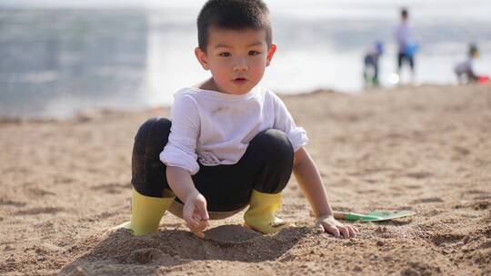 小男孩在河边的沙滩上挖沙子堆城堡