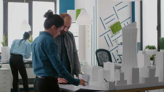 建筑师团队使用桌面上的蓝图和建筑模型进行规划设计