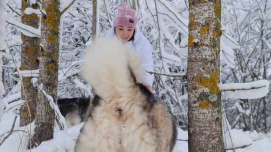 女人在白雪覆盖的树林里和她的狗玩耍