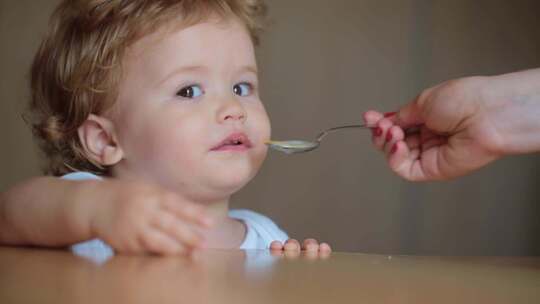 一个可爱的婴儿用勺子吃饭饥饿的小孩子吃孩