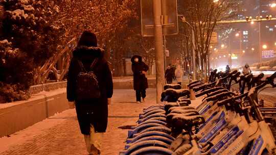 夜晚行人雪中行走城市街道