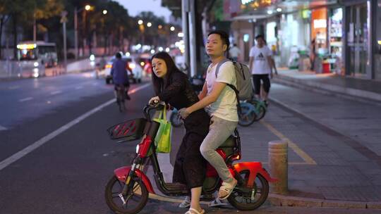 街上情侣骑一辆共享电动车