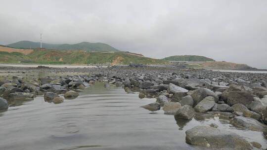 行走在海边黑礁石浅滩