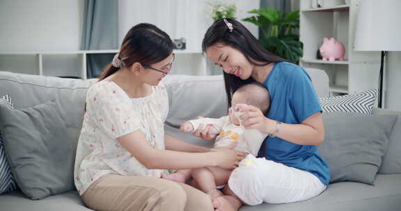 两个年轻的亚洲女人在家里开心地和一个婴儿