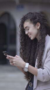 开朗的摩洛哥女孩在她的智能手机户外侧视图