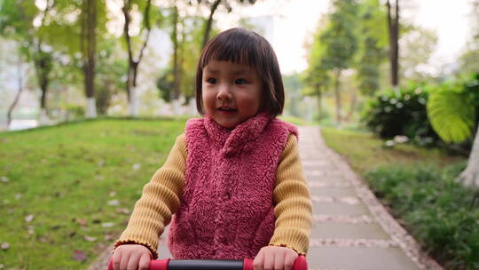 慢镜头特写小女孩在公园里骑车