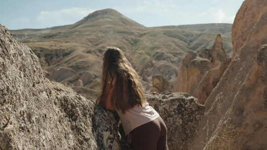 一个年轻女人在古老的石头山谷里凝视着一座
