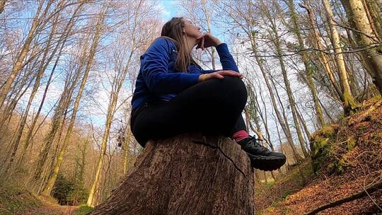 一个女人坐在树墩上仰拍视角