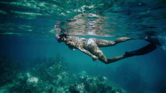 女人在海洋珊瑚礁上浮潜