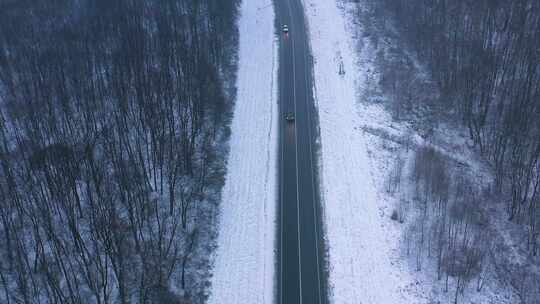 冬季森林里雪地公路上行驶的汽车