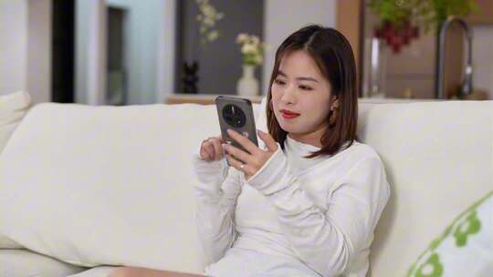 女子沙发休闲刷视频看窗外思考