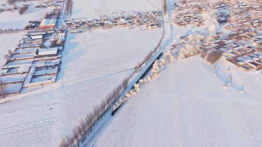 航拍中国东北冬季雪景中的蒸汽火车穿过村庄