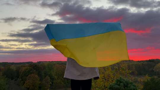 4K日落时，女孩举着乌克兰国旗