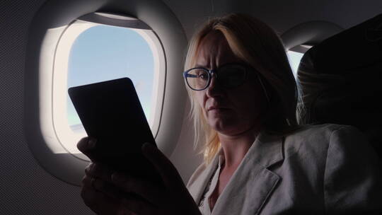商务女性在飞机上阅读电子书