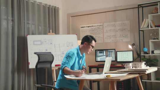 亚洲男工程师在办公室的白板上用笔记本电脑绘制蓝图