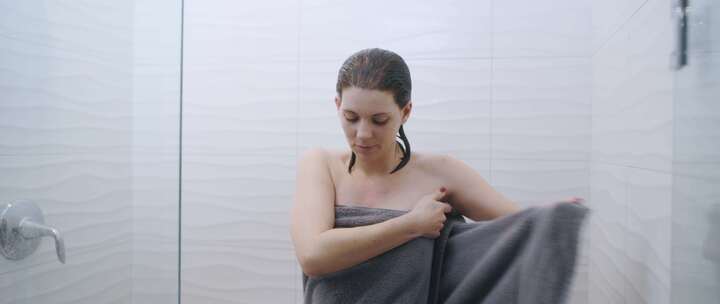 站在淋浴间用毛巾裹着身体的女人