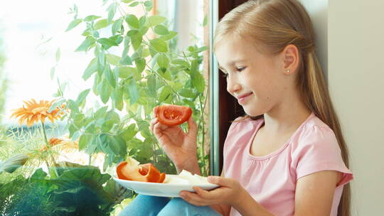 女孩坐在飘窗上吃番茄