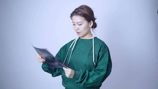 身穿手术服,手拿X光片医学影像的亚洲美女
