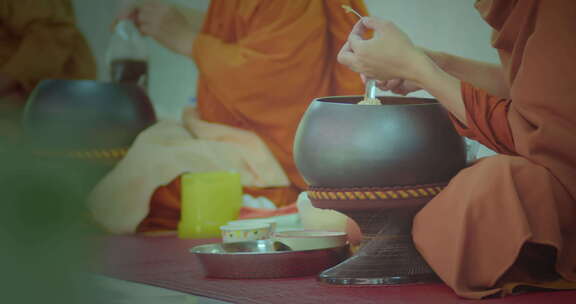 佛教僧侣们在人们功德后，把食物舀进他们的