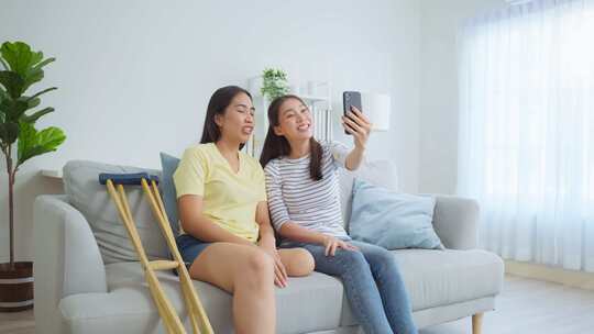 亚洲女性截肢者和朋友在家里使用手机视频通话。