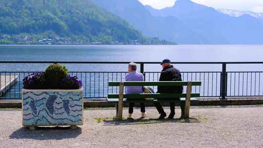 一对老人安逸的坐在湖边公园长椅上视频素材模板下载
