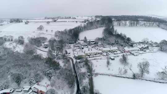 空中跟踪在一个被雪覆盖的古雅的英国村庄上空。栖息在山坡上高清在线视频素材下载