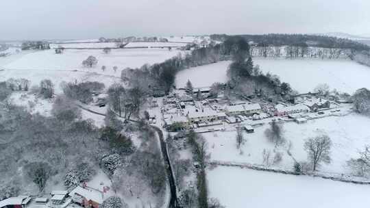 空中跟踪在一个被雪覆盖的古雅的英国村庄上空。栖息在山坡上