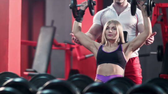 女人和她的私人教练在健身房用杠铃锻炼