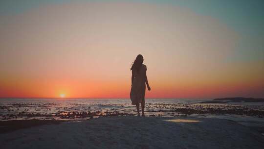 美女站在海边望向远处的夕阳