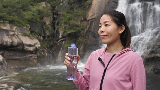 亚洲中国人女性在瀑布下喝水饮用水