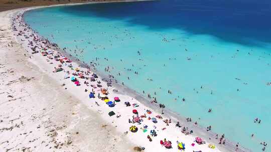 人们在清澈的热带绿松石浅蓝色大海的白色沙滩上度假游泳