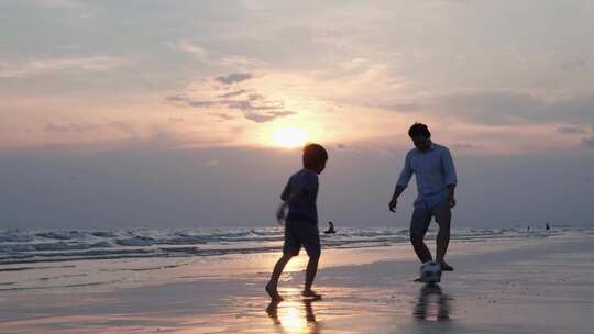 父子俩在海边沙滩上玩足球