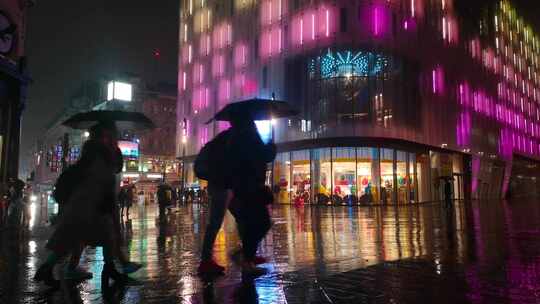 雨夜行人撑伞走过霓虹大楼