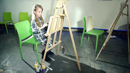 可爱的小女孩正在用画笔和油漆画画