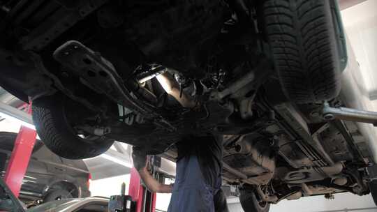 汽车修理厂修理师傅在检修汽车底盘