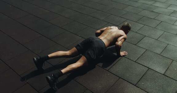 肌肉发达的男人在外面做俯卧撑运动