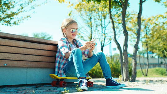 坐在滑板上玩手机的女孩