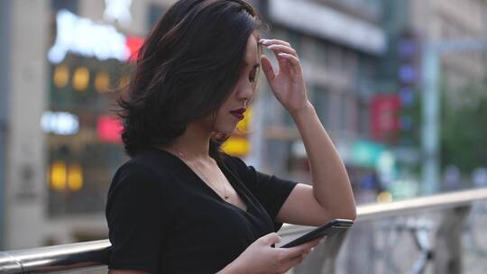 夏日城市女青年在街边看手机用手撩头发