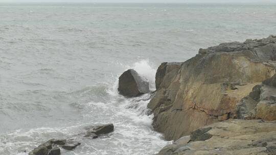 海边浪花拍打礁石，沙滩