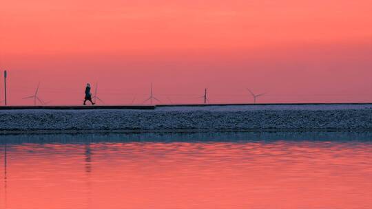 冬天夕阳雪山湖面下孤独行走的一个少女剪影