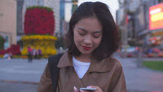 都市美女在城市傍晚街道走路看手机