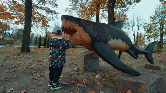 好奇的蹒跚学步的孩子穿着暖和的衣服站在鲨