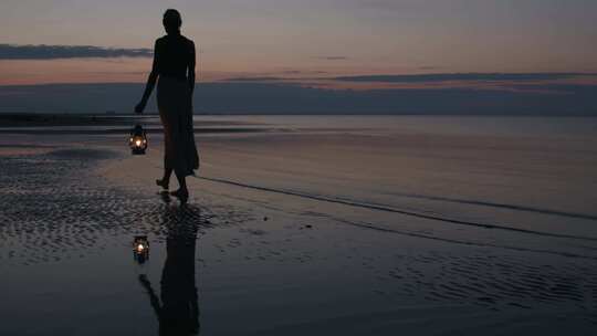 黄昏时女生提着灯在沙滩行走