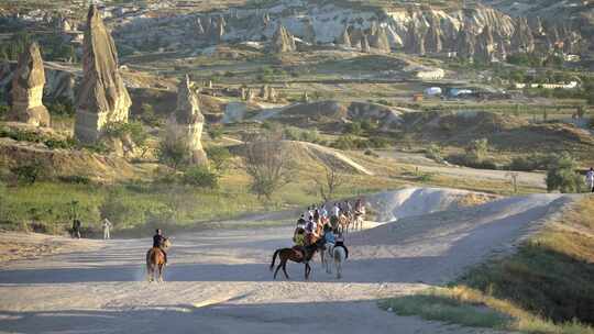 在卡帕多西亚的Hoodoo仙女烟囱中进行旅游旅行和骑马散步的游客